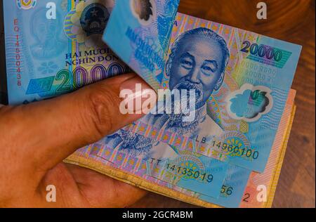 Die männliche Hand hält einen Fan der vietnamesischen Dong-Banknote, der Währung Vietnams. Nahaufnahme Polymer Money of Vietnam. 20000 Dong oder VND in männlicher Hand. In Fro Stockfoto