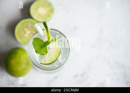 Exotische Sommergetränke erfrischende kalte Getränke Gläser frisches Obst auf Eis hausgemachter Cocktail-Tee mit Mojito-Zitronenlime und Minzblatt, farbenfroher Sommer Stockfoto