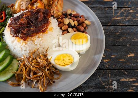 Nasi Lemak ist ein Reisgericht, das mit Kokosrahm angereichert und mit frittiertem Fisch oder gebratenem Huhn beladen ist. Stockfoto