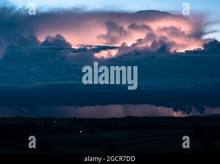 Ein abendliches Gewitter wird von innen durch Blitze beleuchtet Stockfoto