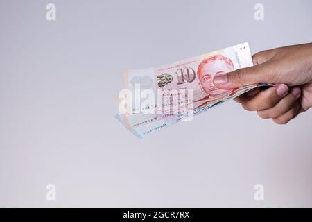 Singapur-Dollar in weiblicher Hand. Die Hände der Frau zeigen singapurische Dollar-Banknoten. Mädchen halten Geld von Singapur. Asiatische Währung. Nahaufnahme Stockfoto