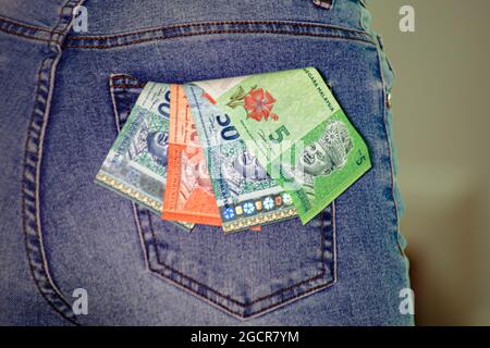 Eine Kollektion von malaysischen Ringgit in einer weiblichen Jeanstasche. Ein Haufen Ringgit in einer weiblichen Jeanstasche. Ringgit Malaysia Notizen stecken in einer Frau Jeans Stockfoto