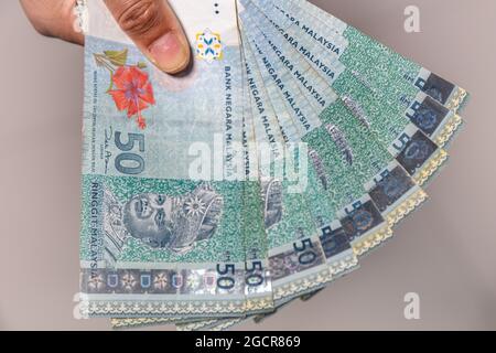 Eine Sammlung von fünfzig malaysischen Ringgit-Banknoten in einer weiblichen Hand. Frau Hand zeigen Malaysia Ringgit Banknoten. Mädchen Hände halten Geld von Malaysia. Stockfoto