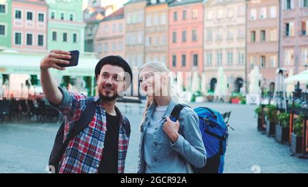 Glückliche junge paar Touristen machen Selfie auf dem Smartphone in der Innenstadt. Sie haben Touristen Taschen. Stockfoto