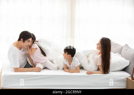 Glückliche junge Familie, die sich im Bett erholte Stockfoto