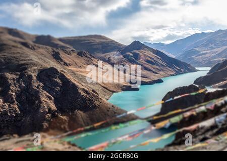 Kong mu Co See auf 5000 Meter über dem Meeresspiegel bei Tibet. Bunte Gebetsfahnen vor dem Wind winken. Türkisfarbenes Wasser im Bergsee. Neigen Stockfoto