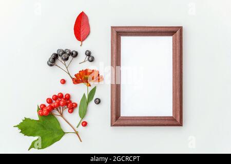 Florale Komposition im Herbst. Vertikaler Rahmen Mockup Apfelbeere Eberesche Beeren bunte Blätter Hundrose Blumen auf weißem Hintergrund. Fallen natürliche Pflanzen Stockfoto