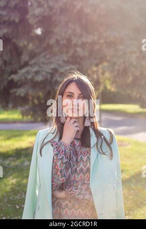 Buntes, ehrliches Porträt einer jungen Brünette während der goldenen Stunde. Sonnenlicht, Hintergrundbeleuchtung Stockfoto