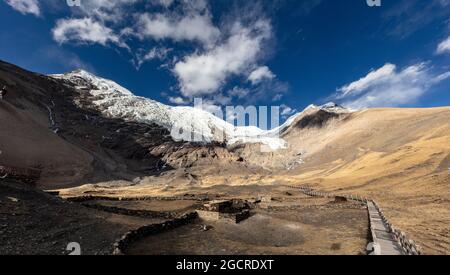 Berggipfel in Tibet - Kangbu-Gletscher auf 5200 Meter über dem Meeresspiegel. Weiße Wolken und blauer Himmel über den hohen Bergen des Himalaya. Schnee auf dem Gipfel Stockfoto