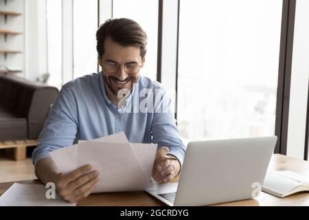 Glücklicher Profi in Brillen Überprüfung der offiziellen rechtlichen Dokumente Stockfoto