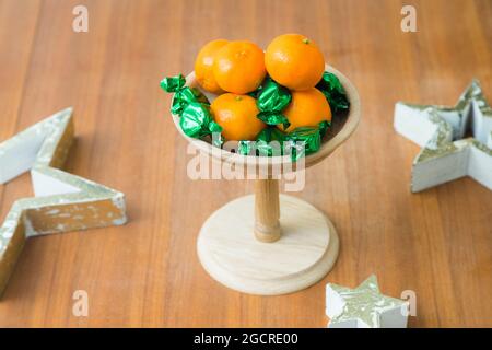 Weihnachts- oder Geburtstagsthema Holztablett mit Süßigkeiten und Mandarinen auf dem Tisch Stockfoto