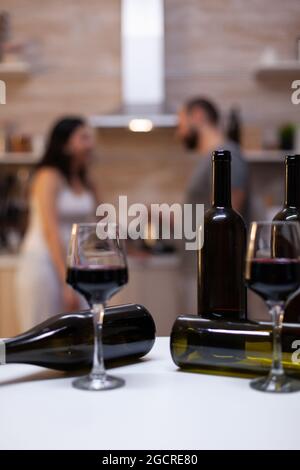 Nahaufnahme von leeren Flaschen mit alkoholischem Getränk und Gläsern mit Wein auf der Küchentheke. Alkohol und Alkohol für berauschtes Paar mit Alkoholabhängigkeit im Hintergrund vorbereitet Stockfoto