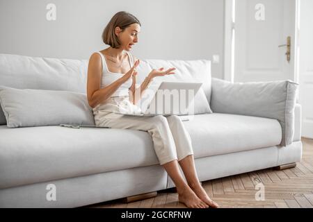 Frau, die online spricht und zu Hause auf der Couch sitzt Stockfoto