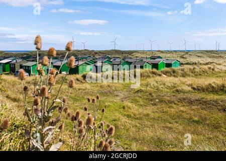 Die fishermens Hütten am South Gare, Redcar, England, Großbritannien mit Offshore- Windenergieanlagen im Hintergrund Stockfoto