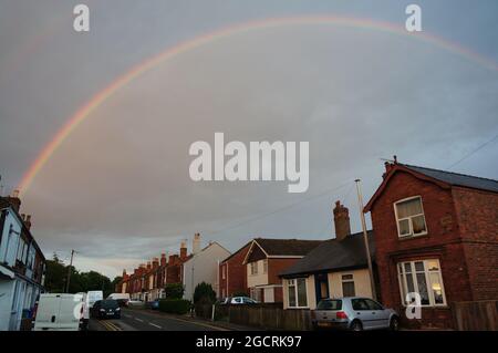 Vorstadtstraße mit einem vollen Regenbogen am Himmel Stockfoto