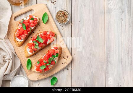 Drei Sandwiches mit Tomaten, Feta und Kräutern auf hellem Holzboden. Italienische, traditionelle Bruschetta. Stockfoto