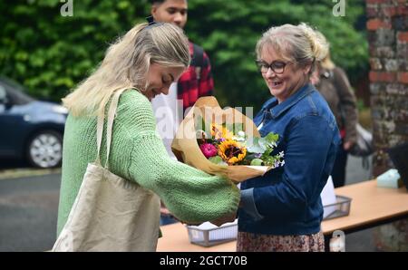 Lewes Sussex UK 10. August 2021 - Studentin des Lewes Old Grammar School in Sussex bringt Blumen für ihre Mitarbeiter, nachdem sie ihre Ergebnisse Der Abitur-Prüfung erhalten hat. In diesem Jahr wurden die Noten aufgrund der Pandemie nicht durch Prüfungen, sondern durch Schätzungen der Lehrer bestimmt. : Credit Simon Dack / Vervate /Alamy Live News Stockfoto