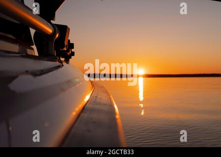 Seitenansicht Beschleunigung angeln Motorboot mit Tropfen Wasser. Blue Ocean Meer Wasser Welle Reflexionen an den Sonnenuntergang. Motorboot im blauen Ozean. Ozean ya Stockfoto