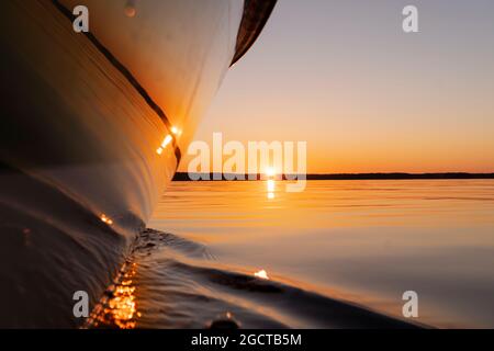 Seitenansicht Beschleunigung angeln Motorboot mit Tropfen Wasser. Blue Ocean Meer Wasser Welle Reflexionen an den Sonnenuntergang. Motorboot im blauen Ozean. Ozean ya Stockfoto