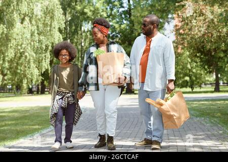 Moderne Familie mit Papptaschen, die am Morgen aus dem Supermarkt nach Hause kommen Stockfoto