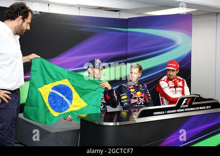 Mark Webber (AUS) Red Bull Racing feiert seinen letzten GP und hält eine brasilianische Flagge, unterzeichnet von Bernie Ecclestone (GBR), CEO der Formel 1 Group (FOM), und allen Fahrern, neben Sebastian Vettel (GER) Red Bull Racing (Mitte), Fernando Alonso (ESP) Ferrari (rechts) und Matteo Bonciani (ITA), FIA Media Delegate (links). Großer Preis von Brasilien, Sonntag, 24. November 2013. Sao Paulo, Brasilien. Stockfoto