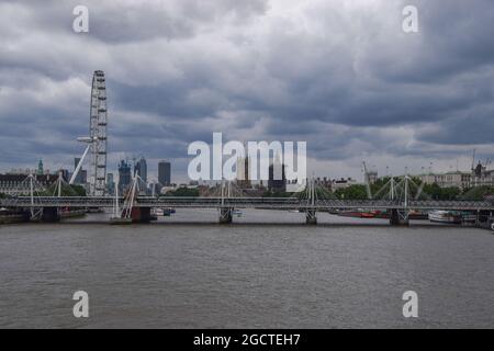 Dunkle Wolken ziehen sich über London Eye, Houses of Parliament und Hungerford und Golden Jubilee Bridges. London, Großbritannien. August 202 Stockfoto