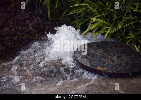 Sintflutartige Regenstürme im Fahrerlager werfen Mannlochabdeckungen auf. Großer Preis von Malaysia, Samstag, 29. März 2014. Sepang, Kuala Lumpur, Malaysia. Stockfoto