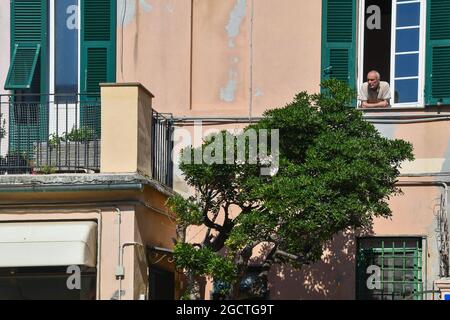 Älterer Mann, der sich aus dem Fenster eines typischen Hauses im Fischerdorf Boccadasse, Genua, Ligurien, Italien, lehnt Stockfoto