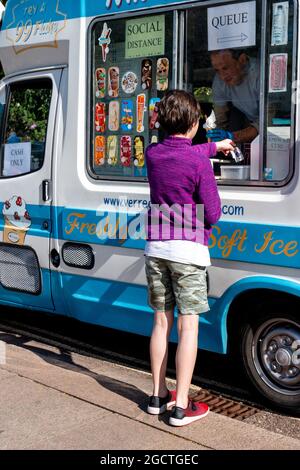 Ein Kind in Sommerkleidung kauft an einem sonnigen Tag in einem Eiswagen ein Eis. Cambridge, Großbritannien Stockfoto