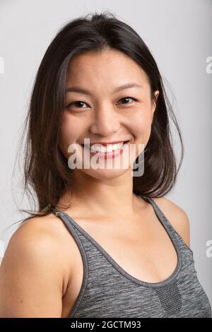 Portrait schöne asiatische Mädchen mit großem Lächeln und braunen Haaren. Sportswear und Lippenstift. Weißer Hintergrund Stockfoto