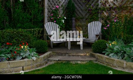 Wunderschöner, farbenprächtiger Garten (modernes Design, geschwungene Wände, dekorative Chiminea, Terrassen, Lichter in der Abenddämmerung) - Yorkshire England Großbritannien Stockfoto