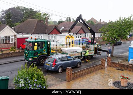 Ein Travis Perkins-Tieflader liefert Baumaterialien zu einem Vorstadthaus in Shepperton, Surrey, England Stockfoto