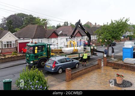 Ein Travis Perkins-Tieflader liefert Baumaterialien zu einem Vorstadthaus in Shepperton, Surrey, England Stockfoto