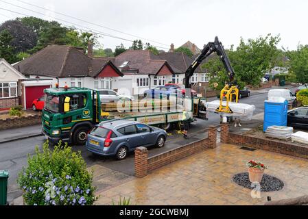 Ein Travis Perkins-Tieflader liefert Baumaterialien zu einem Vorstadthaus in Shepperton, Surrey, England Stockfoto