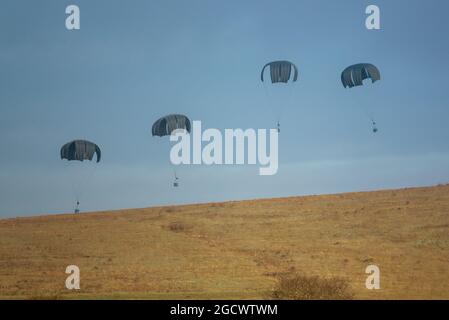 Militärische Palette liefert Fallschirm unten, fallengelassen von einem RAF Airbus A400M Atlas auf einem niedrigen Niveau Pass bei einer militärischen Übung Stockfoto