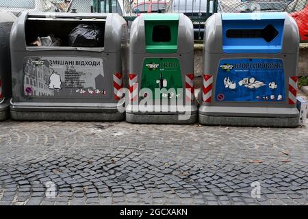 Separate Abfallbehälter für Abfall und recycelte Abfallarten. Konzept der grünen Ökonomie und des Recyclings. Verschiedene Abfallbehälter auf altem Kopfsteinpflaster Stockfoto