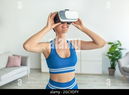 Lächelnde Frau im VR-Headset, die zu Hause trainiert Stockfoto