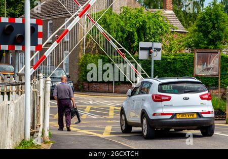 Auto und Tore am automatisierten Bahnübergang auf einer Eisenbahnlinie im Dorf Wainfleet in Lincolnshire East Midlands England Stockfoto