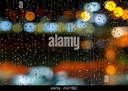 Regentropfen auf einem Fensterglas mit verschwommenen bunten Lichtern im Hintergrund Stockfoto