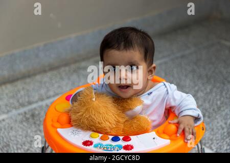 Porträt von niedlichen indischen kleinen Mädchen sitzt in Walker. Stockfoto