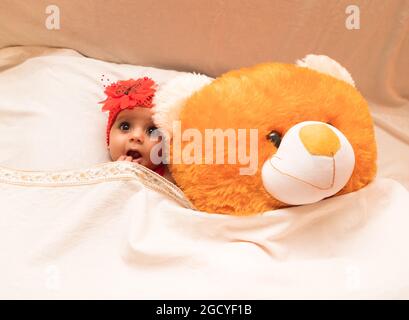 Neugeborenes Baby, neugeborenes Fotoshooting, Nahaufnahme Porträt von niedlichen indischen lächelnden Mädchen, Kleinkind in rotem Kleid. Stockfoto