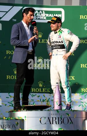 Rennsieger Valtteri Bottas (FIN) Mercedes AMG F1 auf dem Podium mit Mark Webber (AUS) Channel 4 Presenter. Großer Preis von Australien, Sonntag, 17. März 2019. Albert Park, Melbourne, Australien. Stockfoto