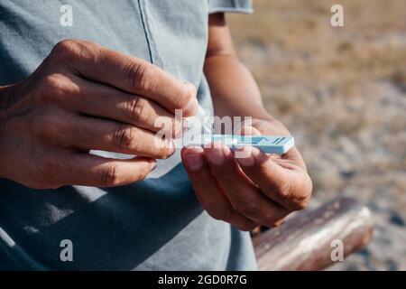 Nahaufnahme eines jungen kaukasischen Mannes, der seine eigene Probe im Sommer in das covid-19-Antigendiagnosetestgerät legt, während er steht Stockfoto