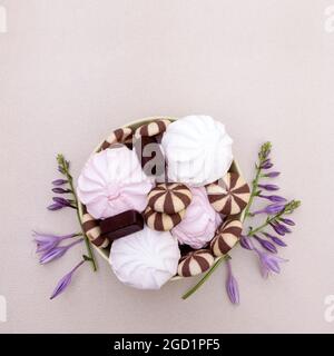 Süßes Dessert aus weißen und rosa Marshallows mit Keksen und Pralinen. Stockfoto