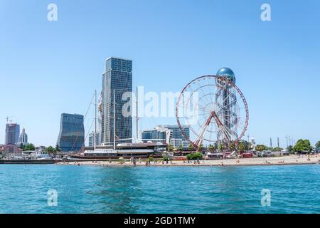 Batumi, Georgia - 2. Juli 2021: Batumi Coastline. Beliebte georgische Urlaubsstadt am Schwarzen Meer. Panoramablick auf das Riesenrad, den alphabetischen Turm, Wolkenkratzer und den Strand vom Meer aus. Stockfoto