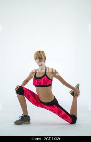 Seitenansicht der schönen sportlichen jungen Frau in roten Sportbekleidung Stretching. Isoliert auf weißem Hintergrund. Kaukasisch, blond. Hochwertige Fotos Stockfoto