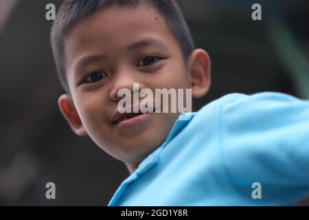 Der süße, aber freche 7-jährige Thai-Junge schaut direkt nach unten zur Kamera Stockfoto