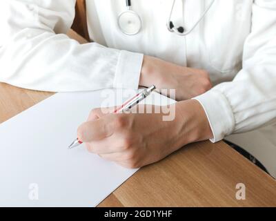 Arzt schreibt auf einem Klemmbrett in der Arztpraxis, Foto Stockfoto