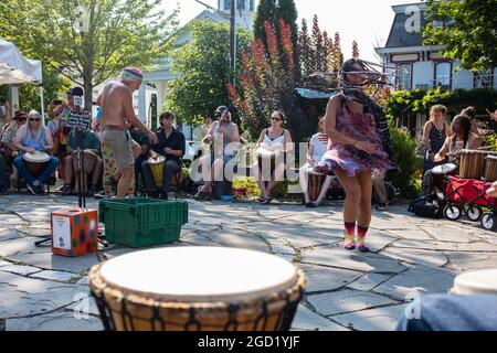 Woodstock, NY, USA - 8. Aug 2021: Ein Mann und eine Frau tanzen zu den Klängen eines Community Drum Circle, der am Sommernachmittag im Village Green stattfindet Stockfoto