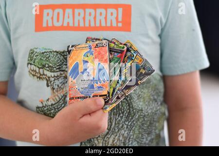 Ein kleiner Junge mit einem Dinosaurier-T-Shirt mit holografischen Pokémon-Karten Stockfoto